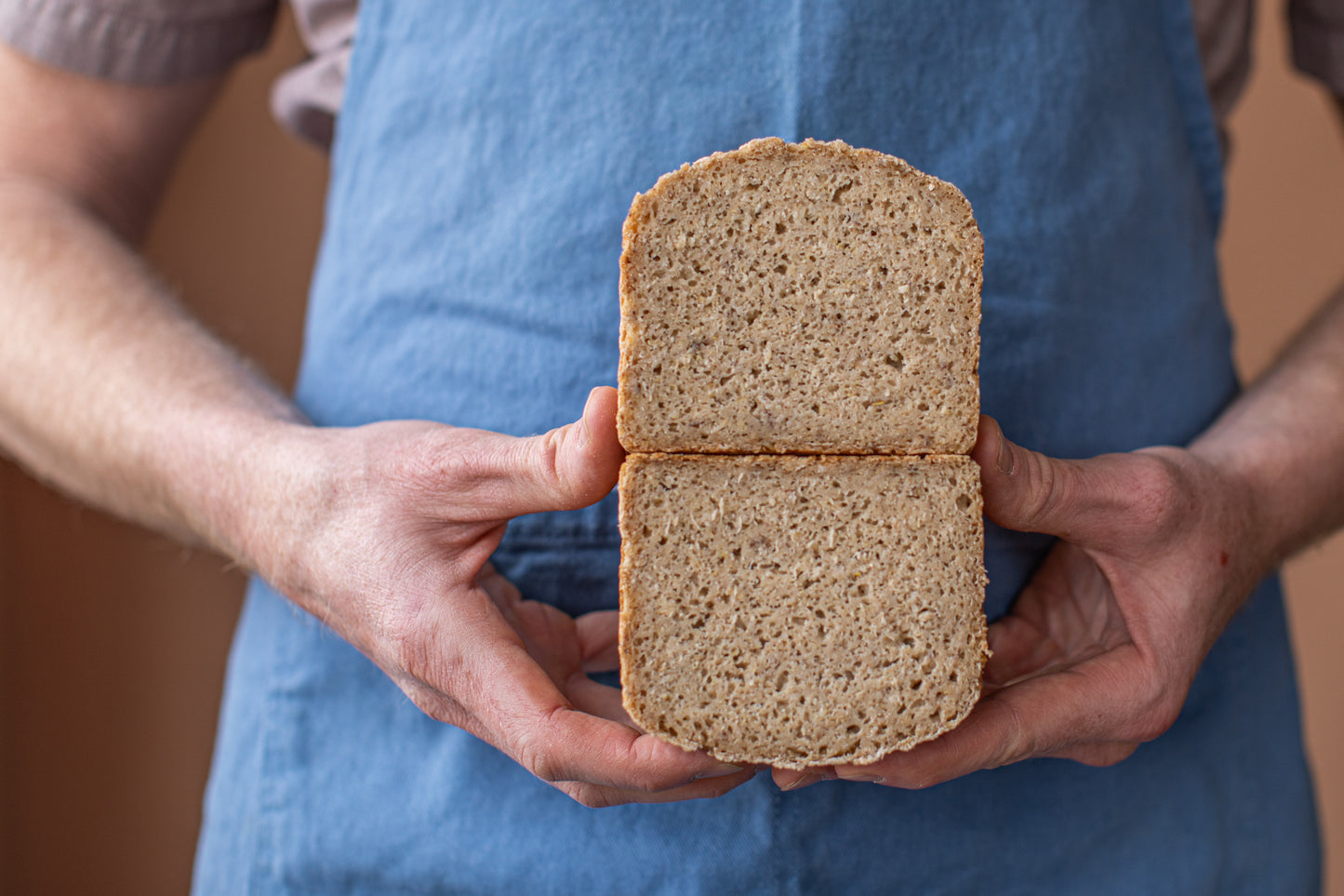 Jeff holding a sliced gluten-free sourdough loaf of bread with a blurred background
